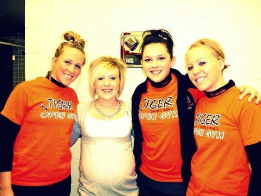 Pregnant teen standing beside her cheerleader friends