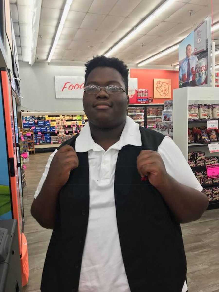 Young man who works at Piggly Wiggly stands smiling in store after helping customer