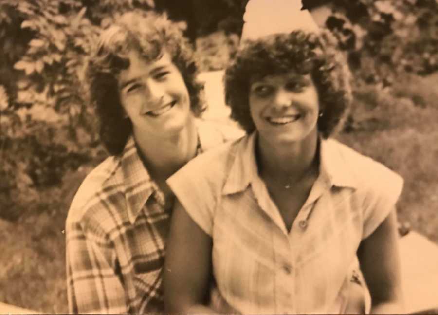 Young couple smile as they sit on ground beside each other