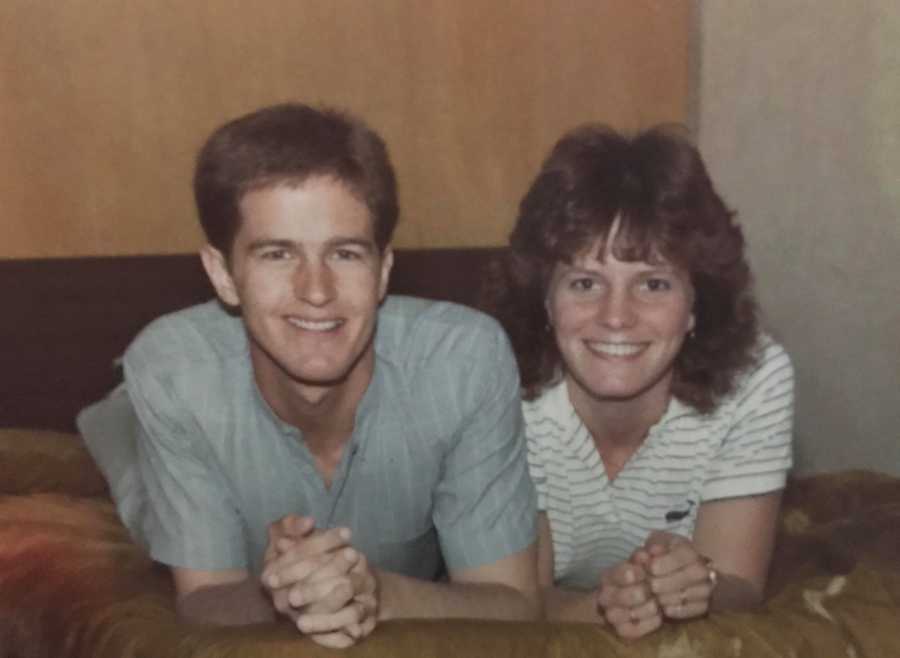 Young husband and wife smiles as they lie on their stomachs beside each other