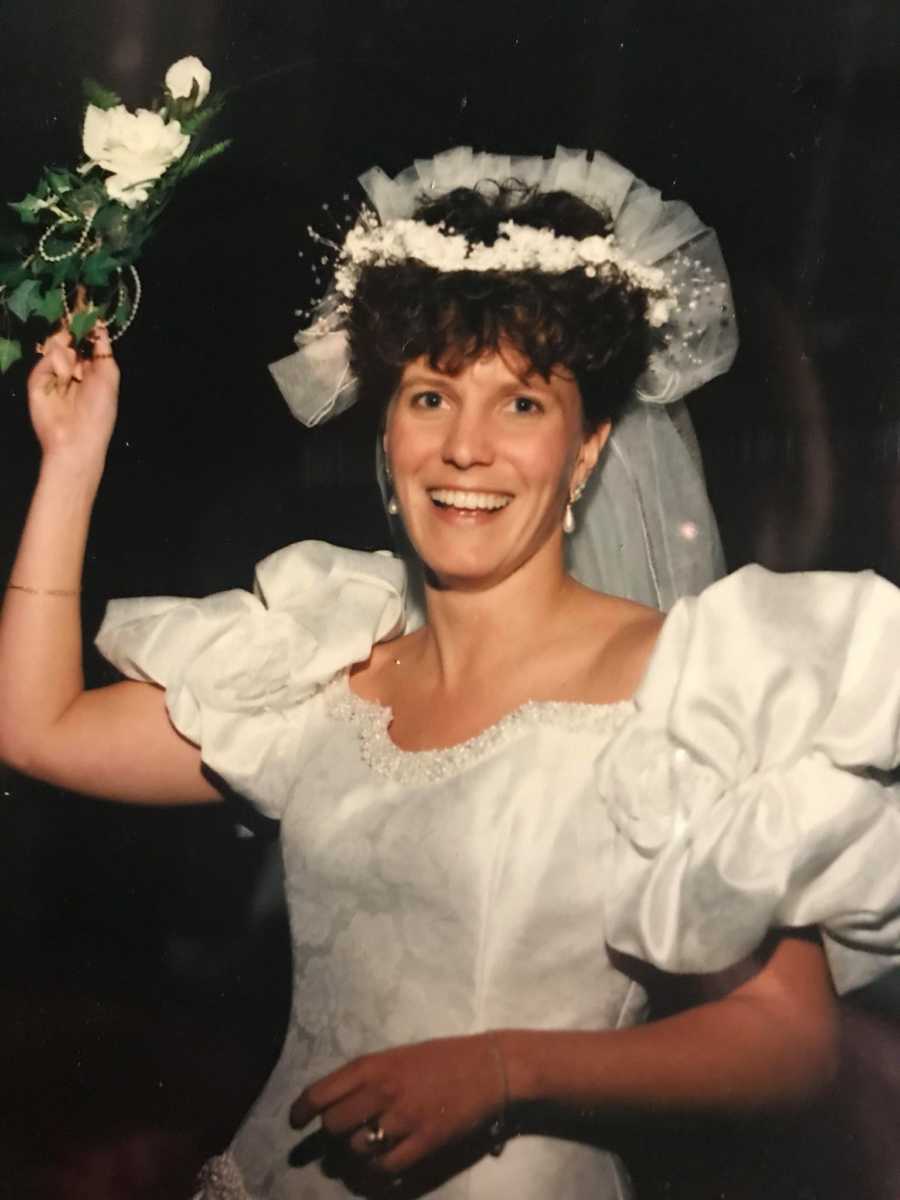 Bride stands in wedding gown smiling 