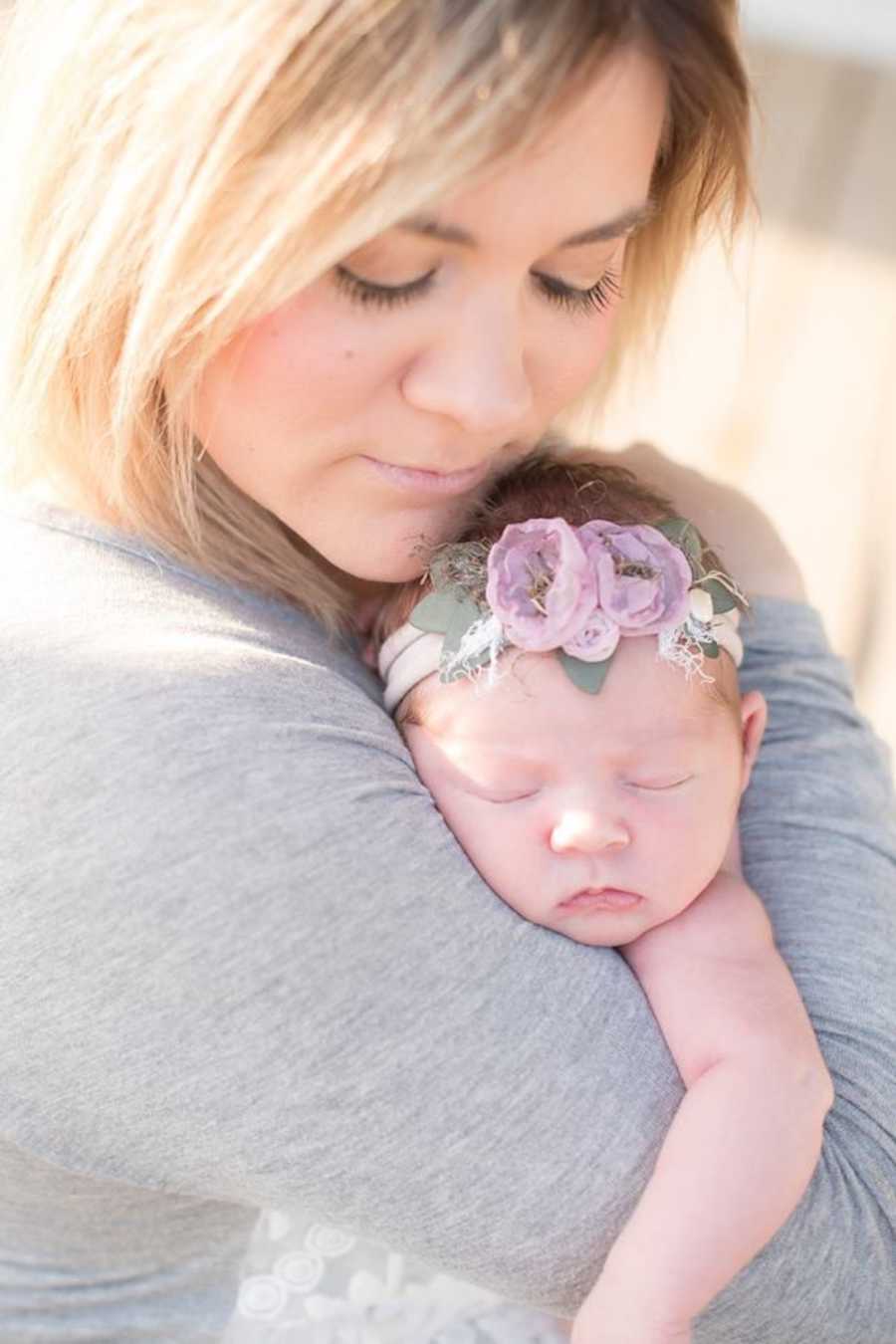 Mother looks down at baby who is sleeping in her arms