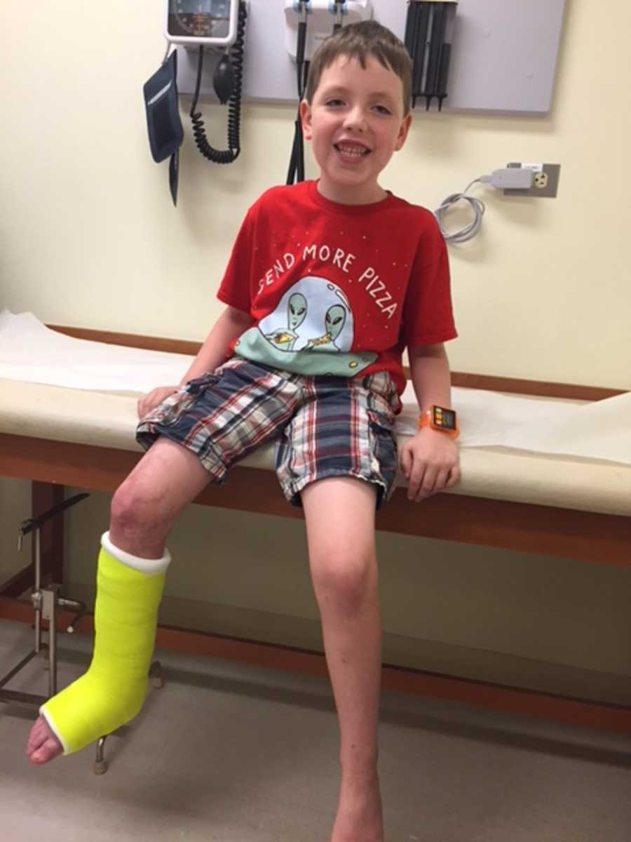 Young boy with CMTC smiling on doctor's office bed with bright yellow cast on his leg