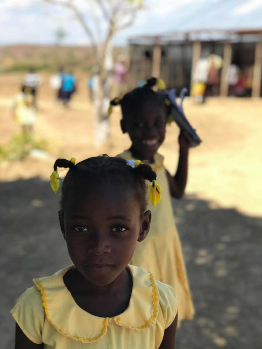 Tw young Haitian orphans standing in matching yellow dresses