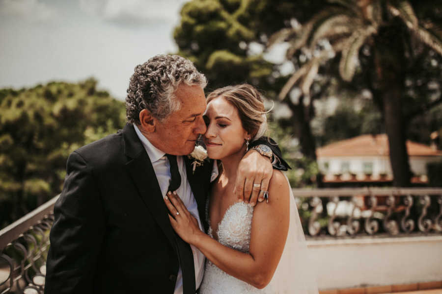 Father stands with arm around his daughter on her wedding day