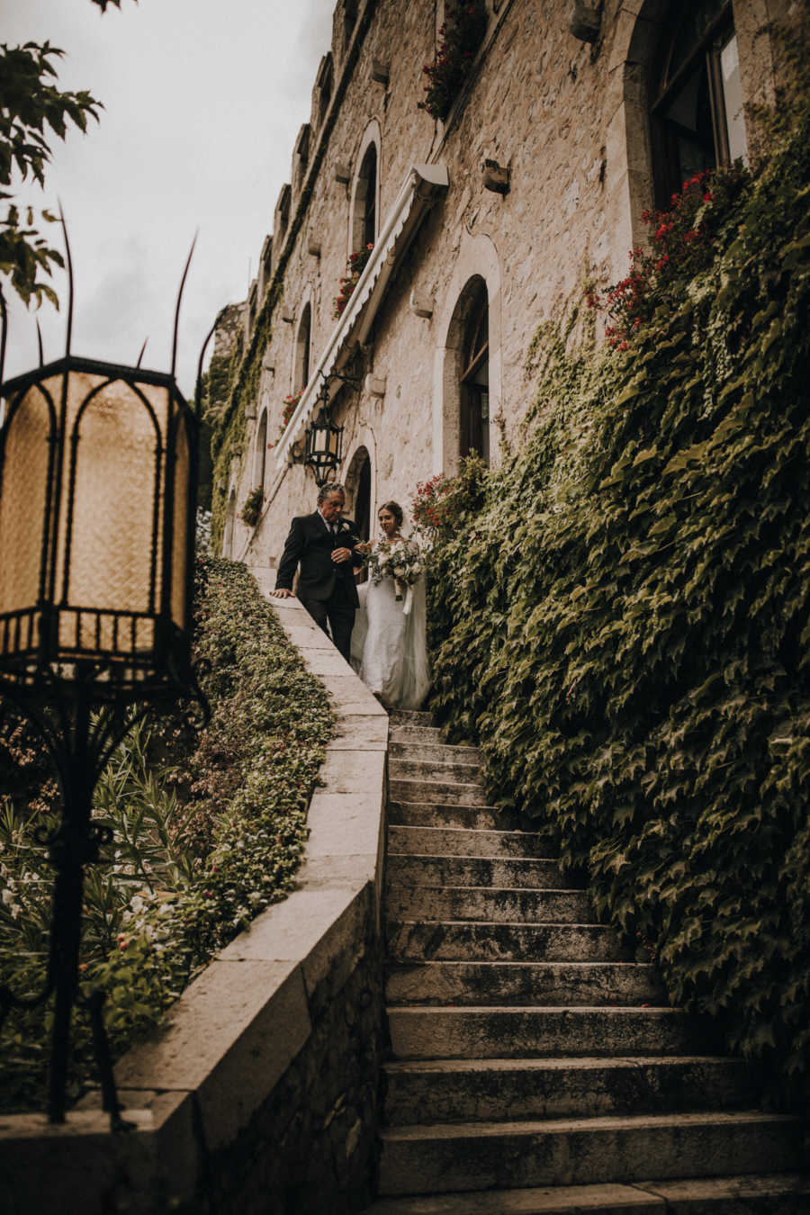 Bride and father walk down stairs outside