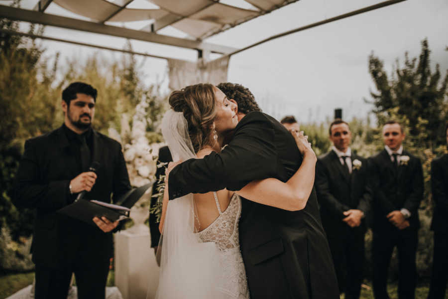 Bride hugs father at altar of outdoor wedding