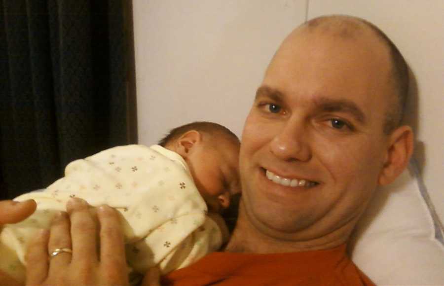 Father smiles as newborn son lays on his chest sleeping