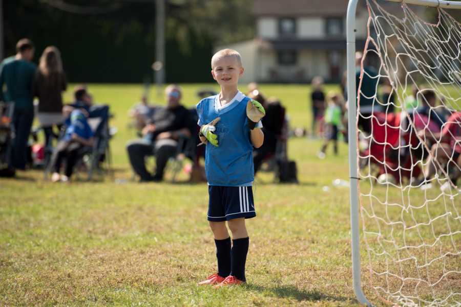 Boy with ADHD smiles as he waves near soccer goal