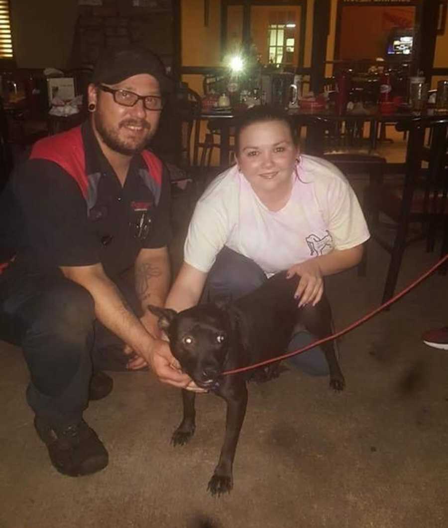 Woman who had miscarriage kneels beside adopted dog and husband