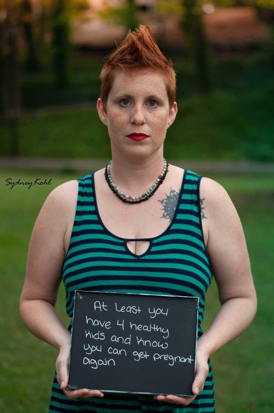 Woman who suffered child loss holds sign that says, "At least you have 4 healthy kids..."