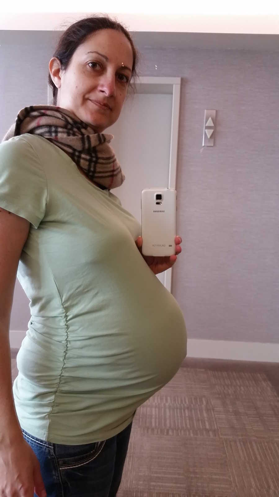 Pregnant woman smiles while taking mirror selfie