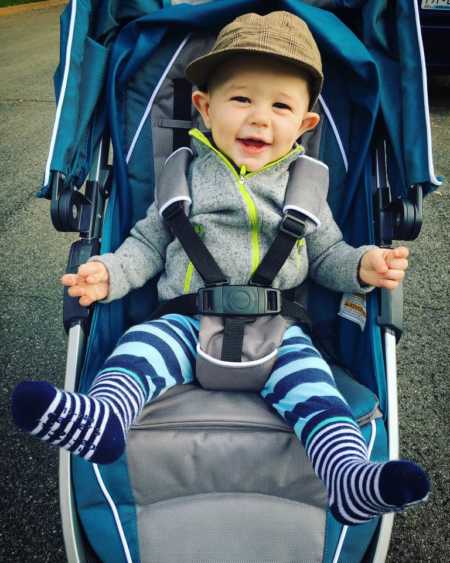 Baby boy sits smiling in blue stroller