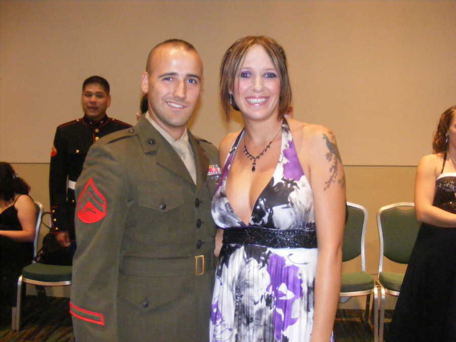 Wife and marine husband stand arm in arm smiling