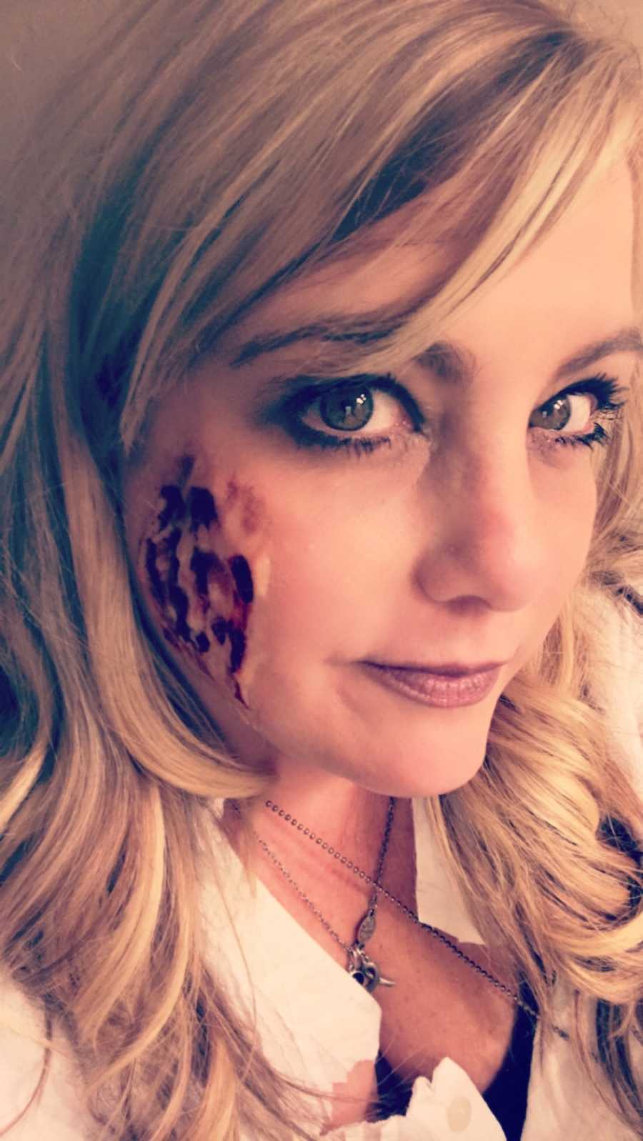 Woman with face painting on for Halloween takes selfie