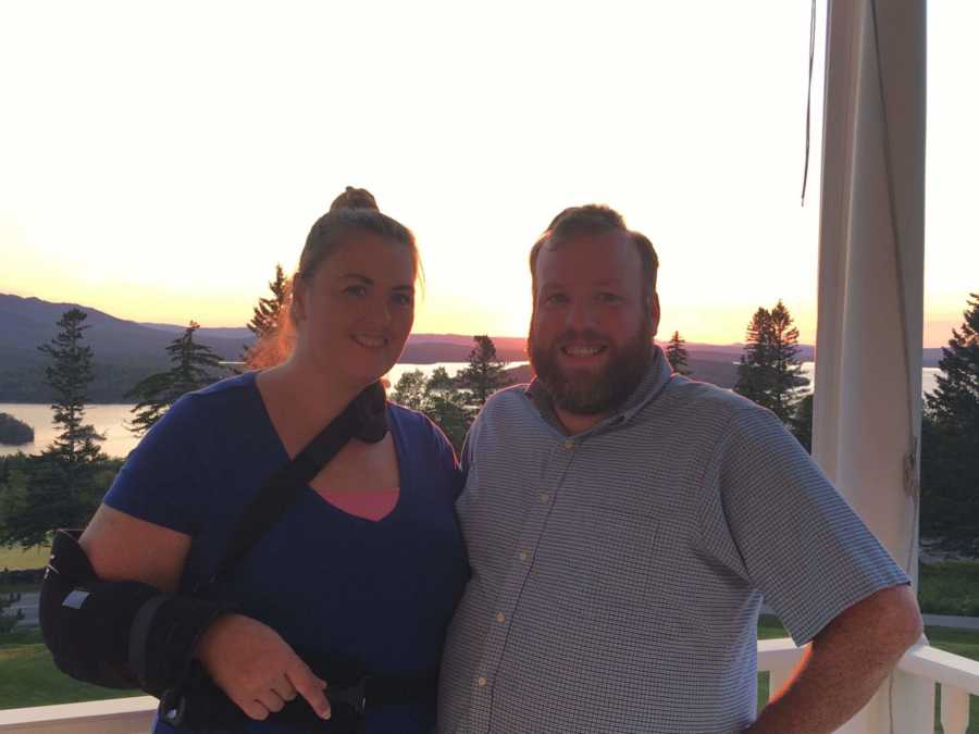 Couple stands on porch that looks out to body of water