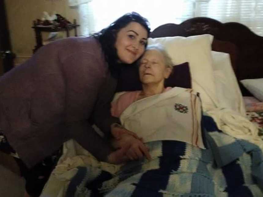 Woman who was having a baby with her wife leans over grandmother with alzheimers who is lying in bed