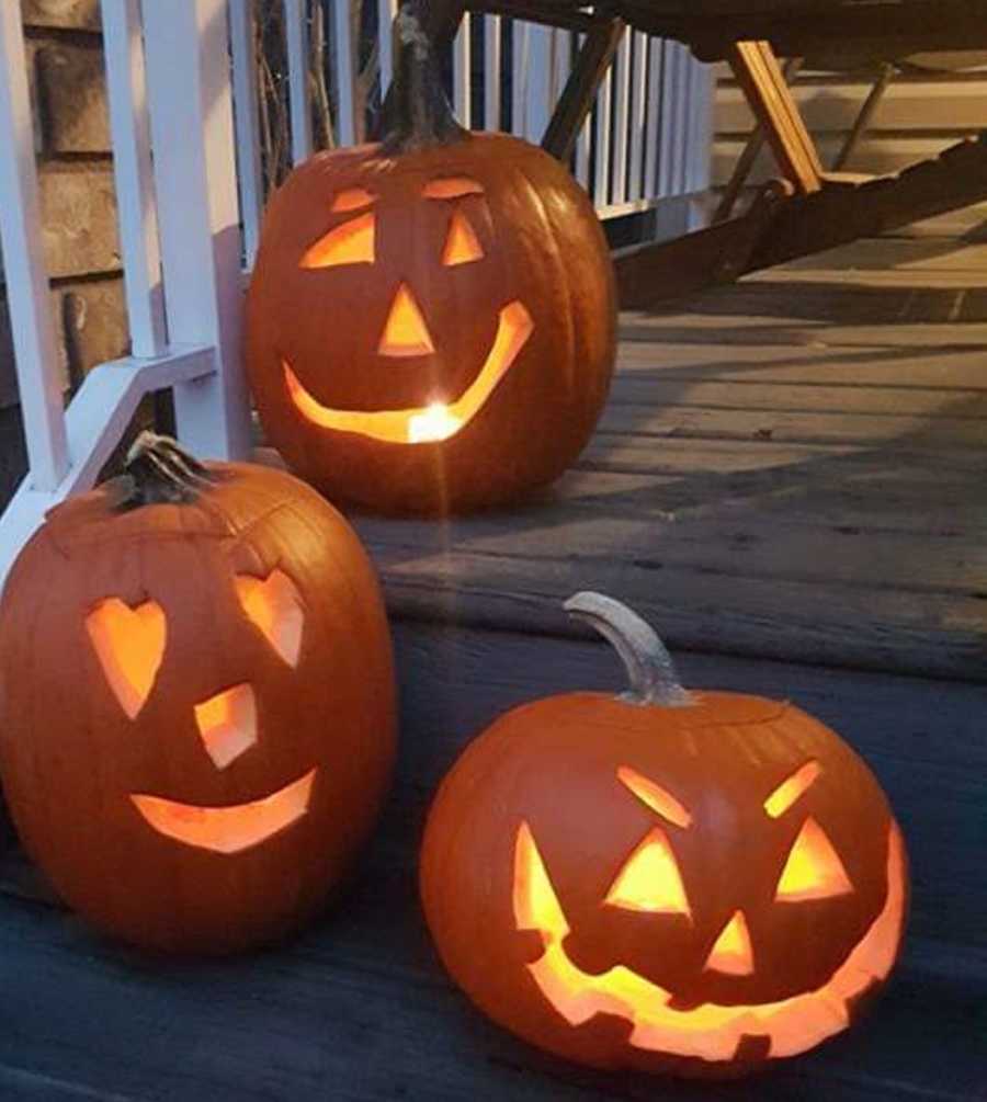 Jack-o-lanterns sit lit up on steps of porch