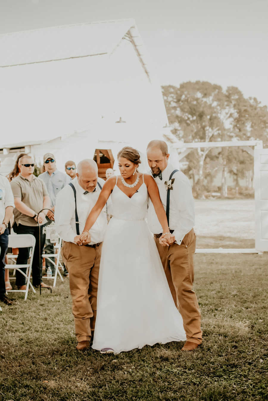 Paralyzed bride walks down aisle with help from two men at outdoor wedding