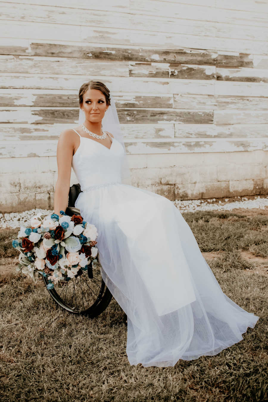 Paralyzed bride sits in wheelchair holding bouquet of flowers
