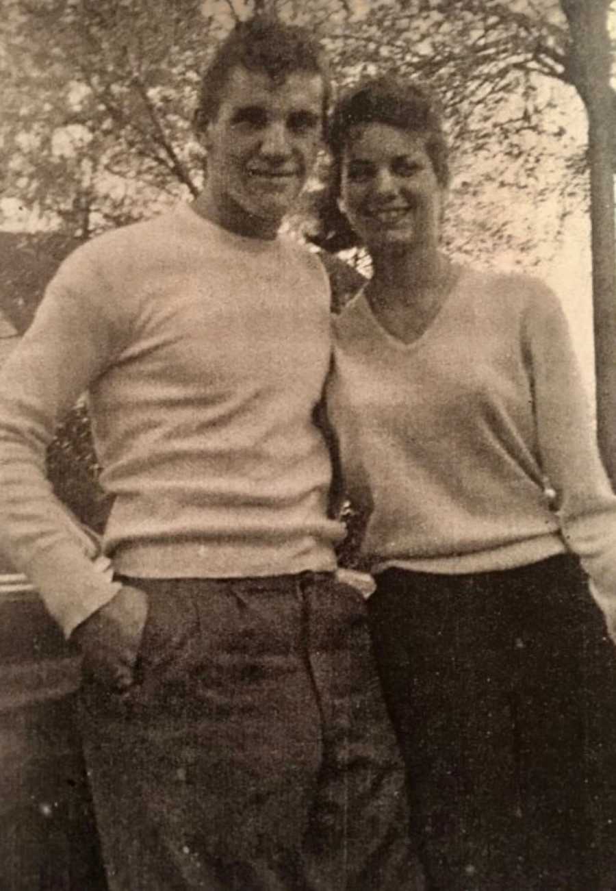 Husband and wife stand arm in arm smiling in blurry old photo