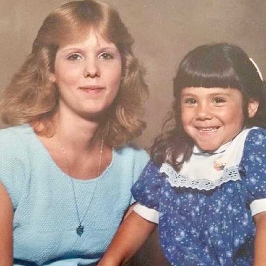 Little girl smiling in dress beside her mother in old portrait