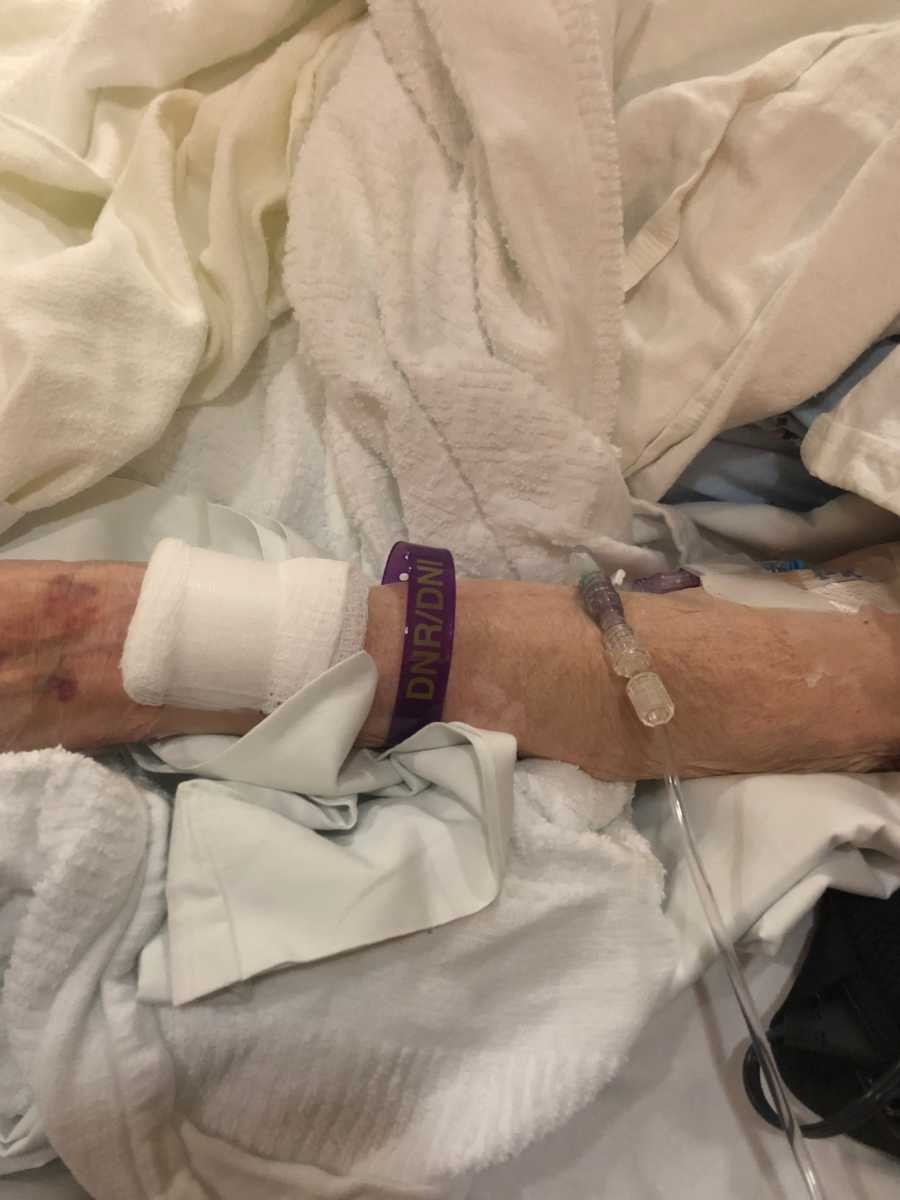 Close up of elderly woman's arm who has purple bracelet on that says, "DNR/DNI"