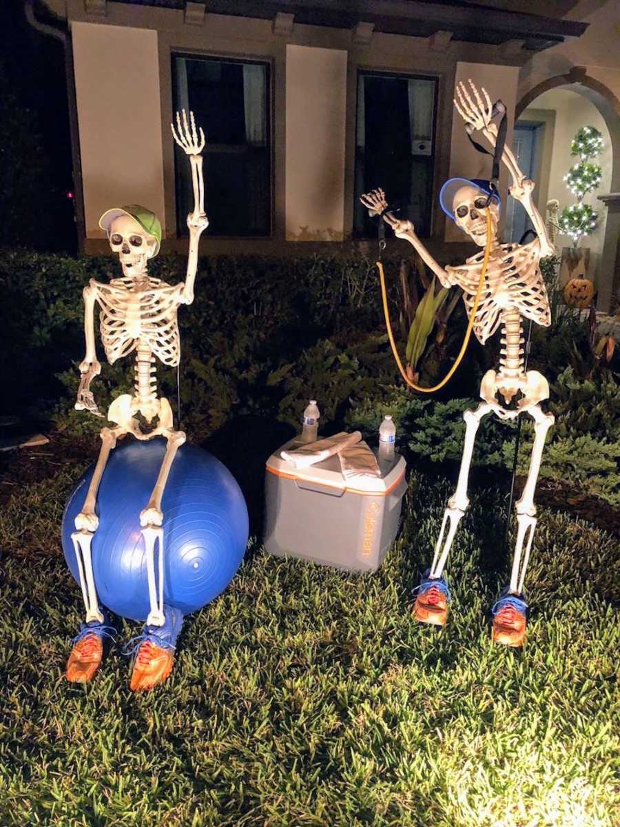 Skeleton sits on medicine ball outside while the other stands holding resistance band
