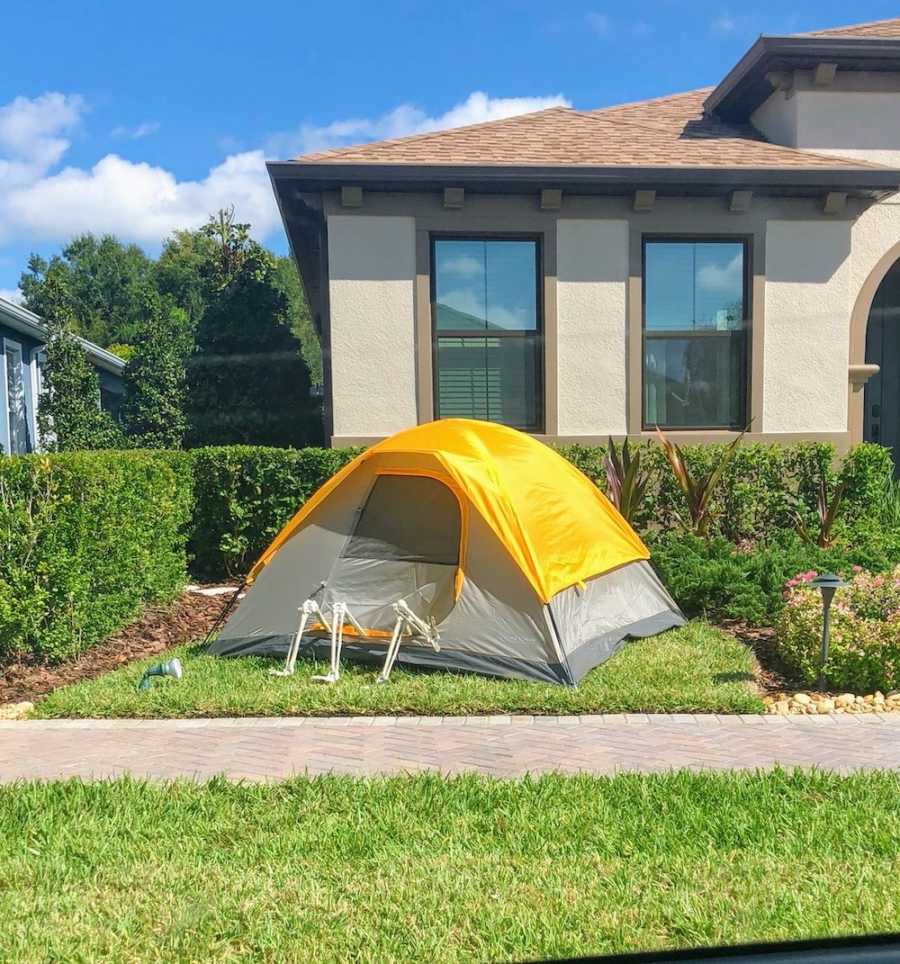 Tent sits in yard with skeletons legs hanging out door flap