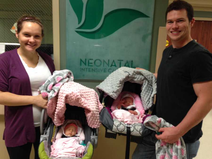 Husband and wife each hold carseat with a twin in it that they are taking home from NICU