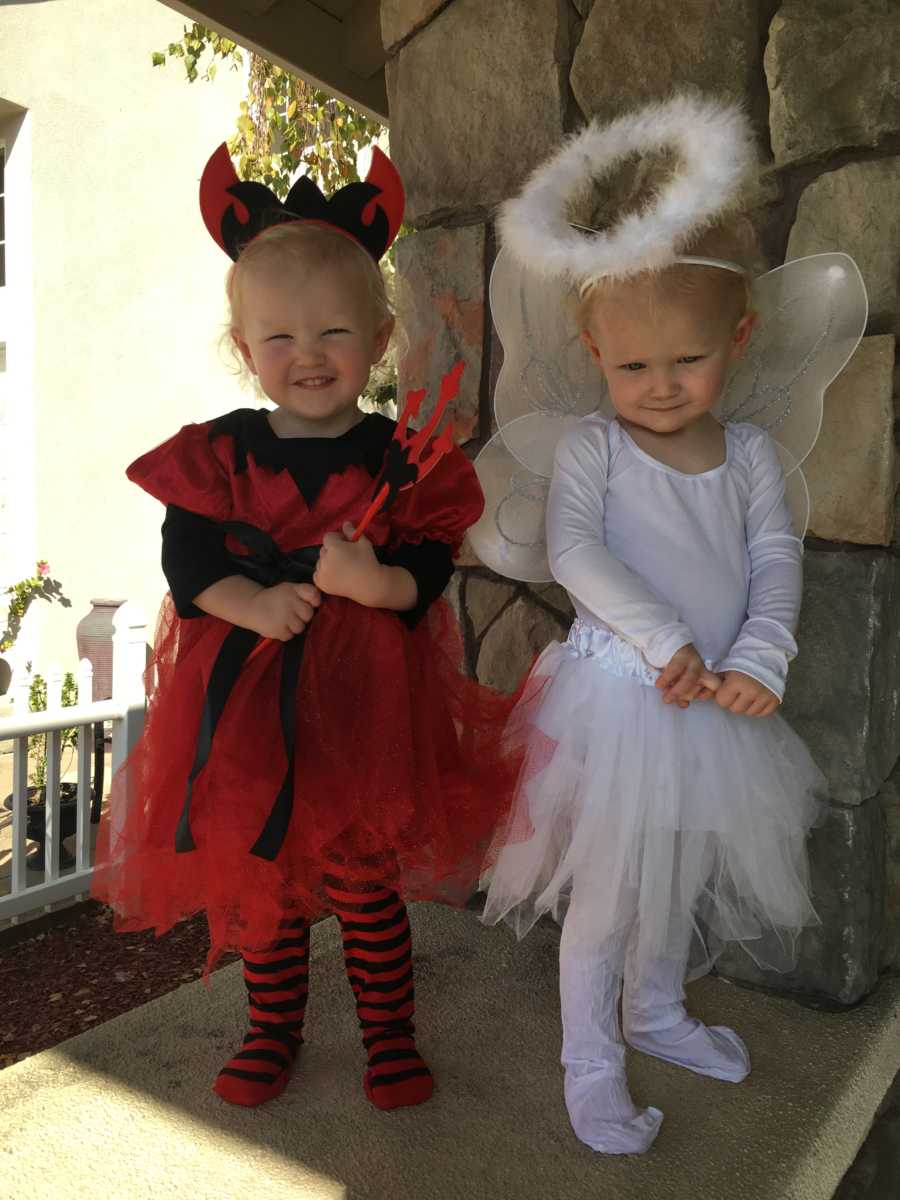 Twin girls dressed as an angel and devil for Halloween