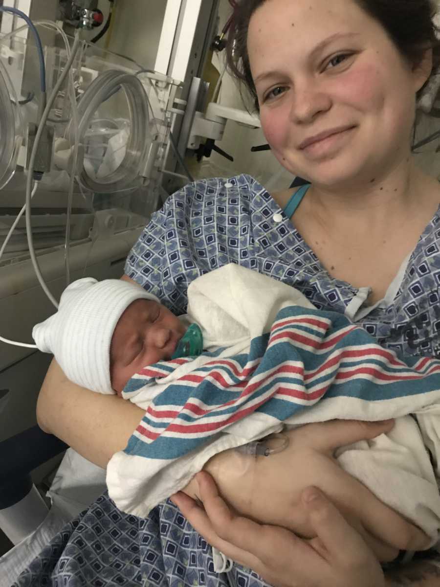 Mother smiles in selfie while holding newborn
