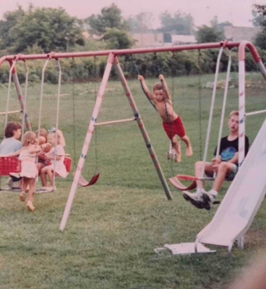 Boy who will later in life die from smoking a heroin-laced joint swinging on swing set with other kids