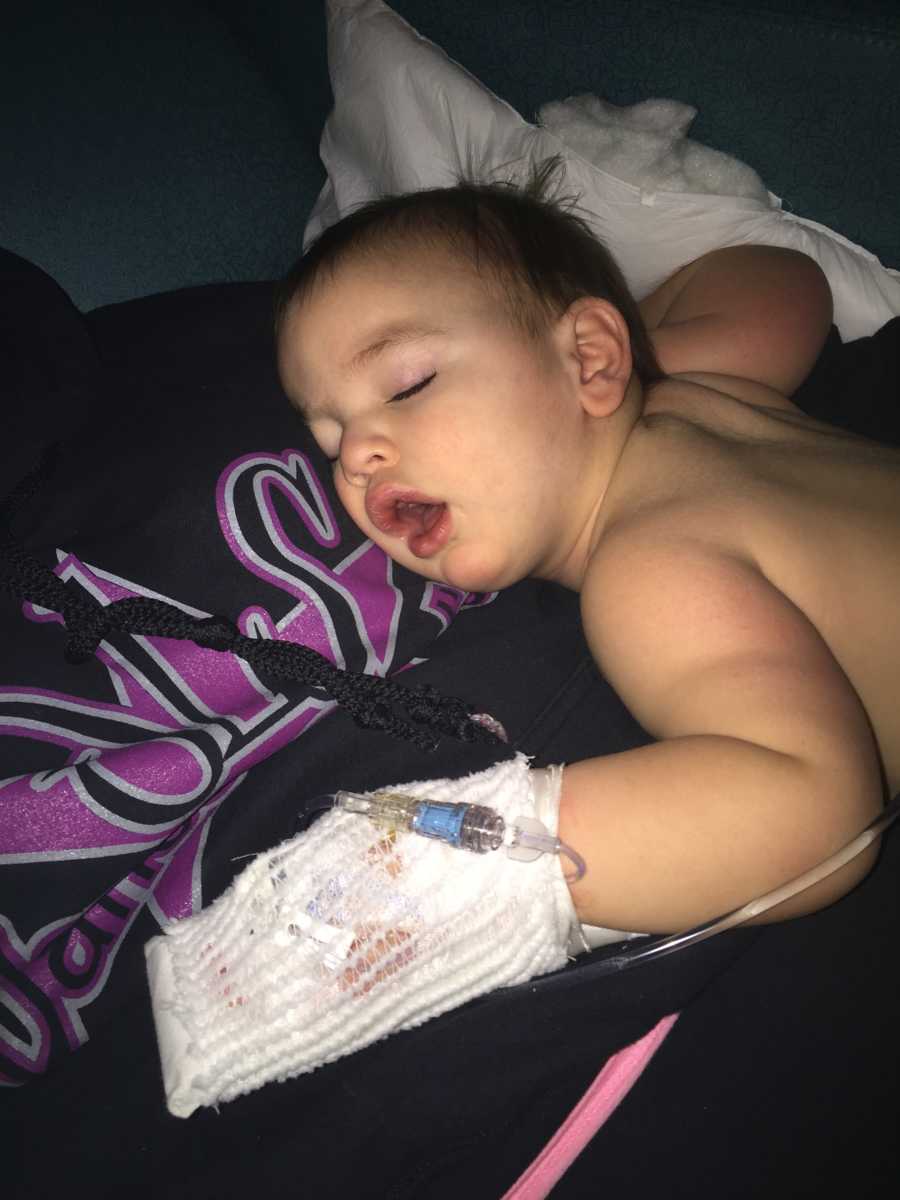 Baby who had seizure lays asleep on mother's chest with bandage on his hand