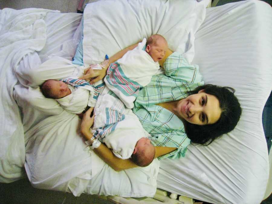 Aerial view of mother lying in hospital bed with triplets in her arms