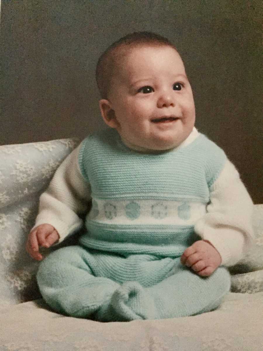 Baby sitting in blue and white onesie in photoshoot