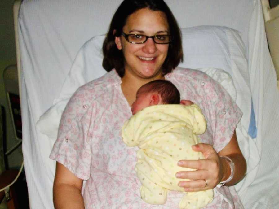 Woman who had HELLP and preeclampsia smiles with newborn laying on her chest in hospital bed
