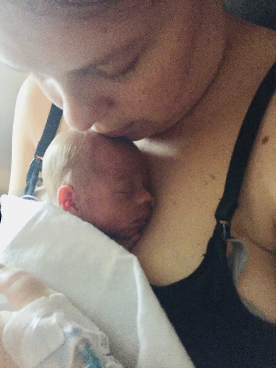 Mother looks down at newborn who is sleeping on her chest