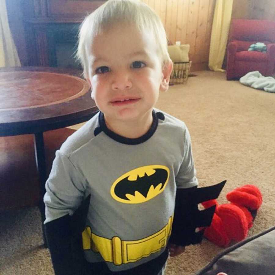 Toddler with Febrile Seizures smiles while wearing Batman costume in home