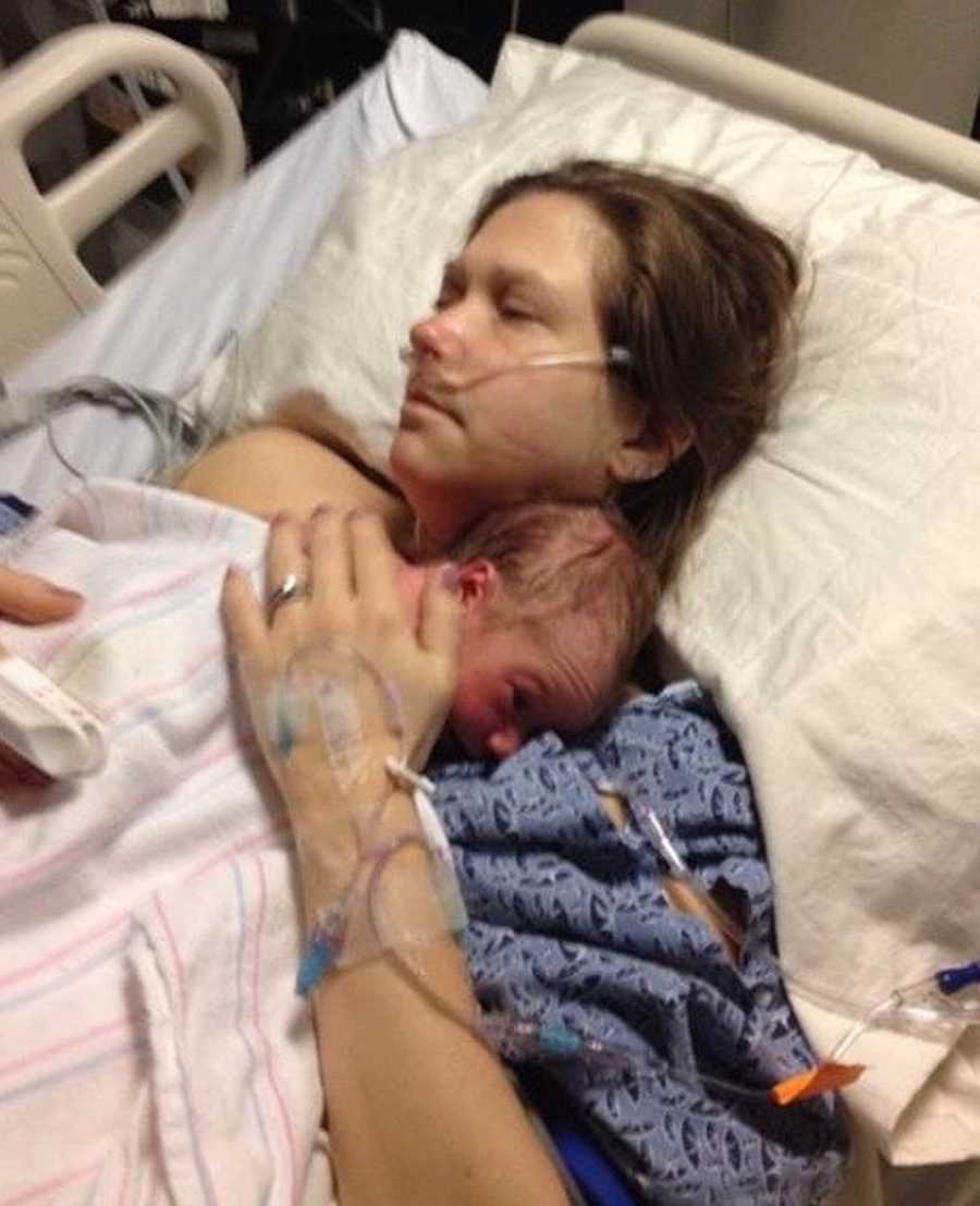 Woman who almost didn't survive child birth lays in hospital bed holding newborn to her chest