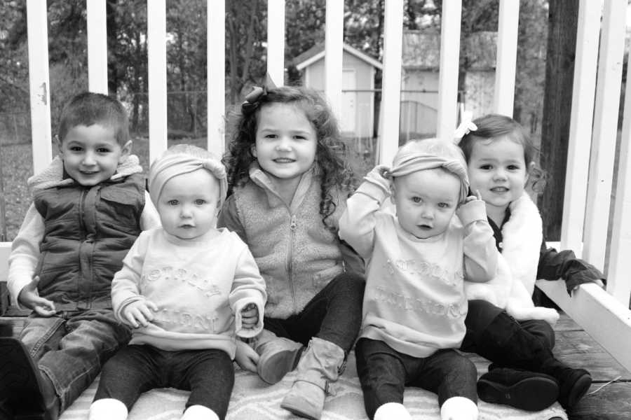 Five young siblings sit on porch smiling