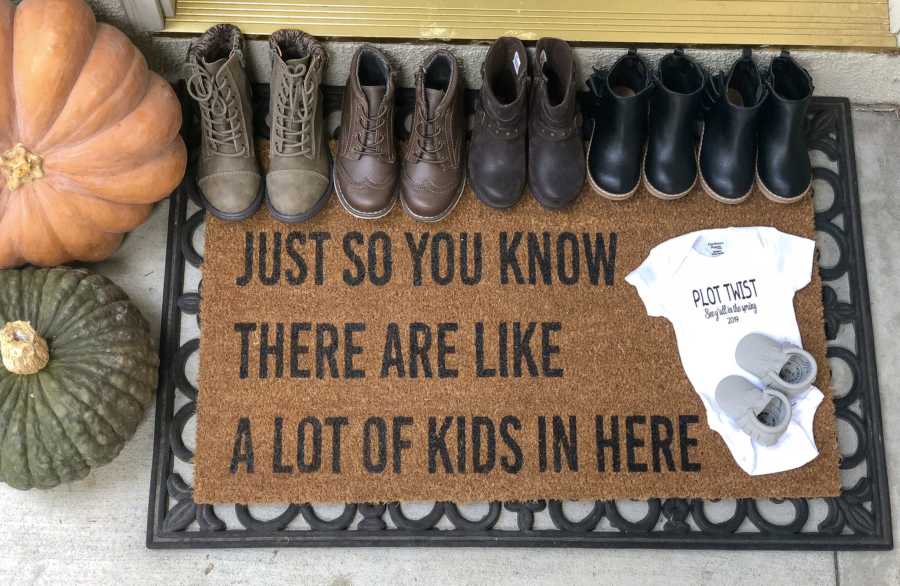 Door mat with shoes and baby onesie on it that says, "Just so you know there are like a lot of kids in here"