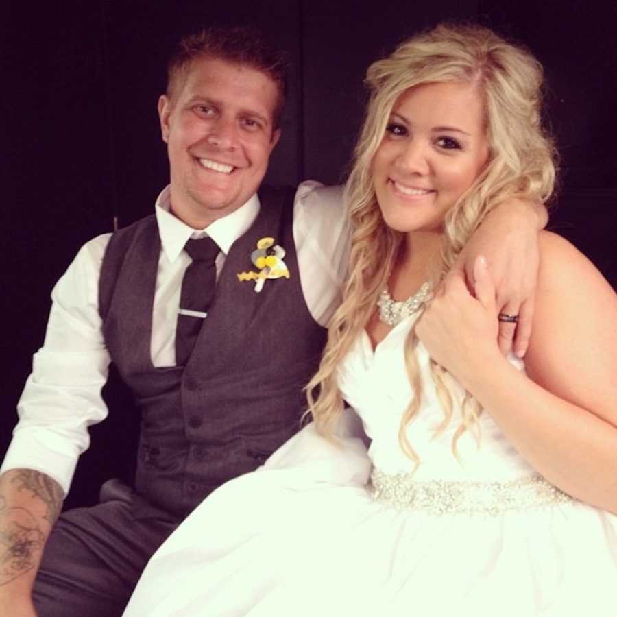 Bride smiles beside groom who has his arm around her