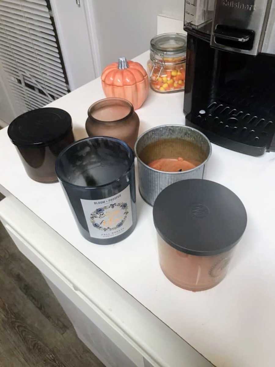 5 candles sitting on kitchen counter that don't have much wax left in them