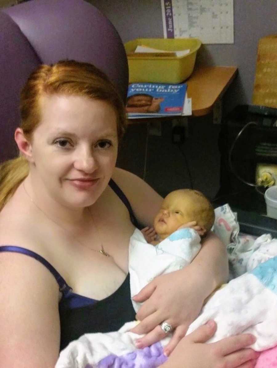 Mother sits in hospital holding newborn daughter who had brain surgery