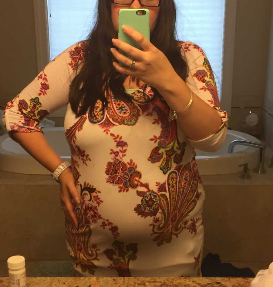Pregnant woman stands with hand on her hip in mirror selfie in bathroom