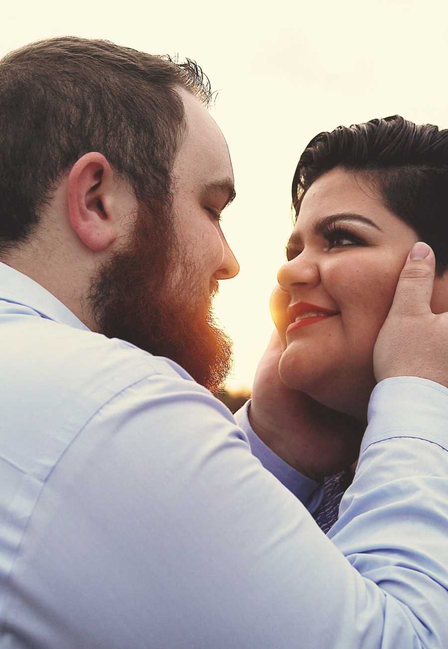 Husband stands holding wife's face who has been suffering from postpartum