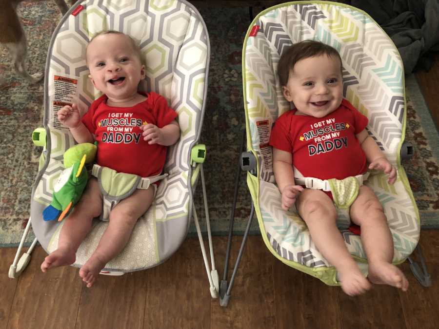 Twin boys of stay at home day sit smiling in floor seats