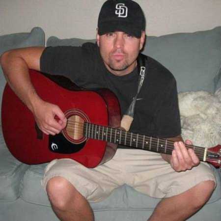 Man sits on couch playing guitar 