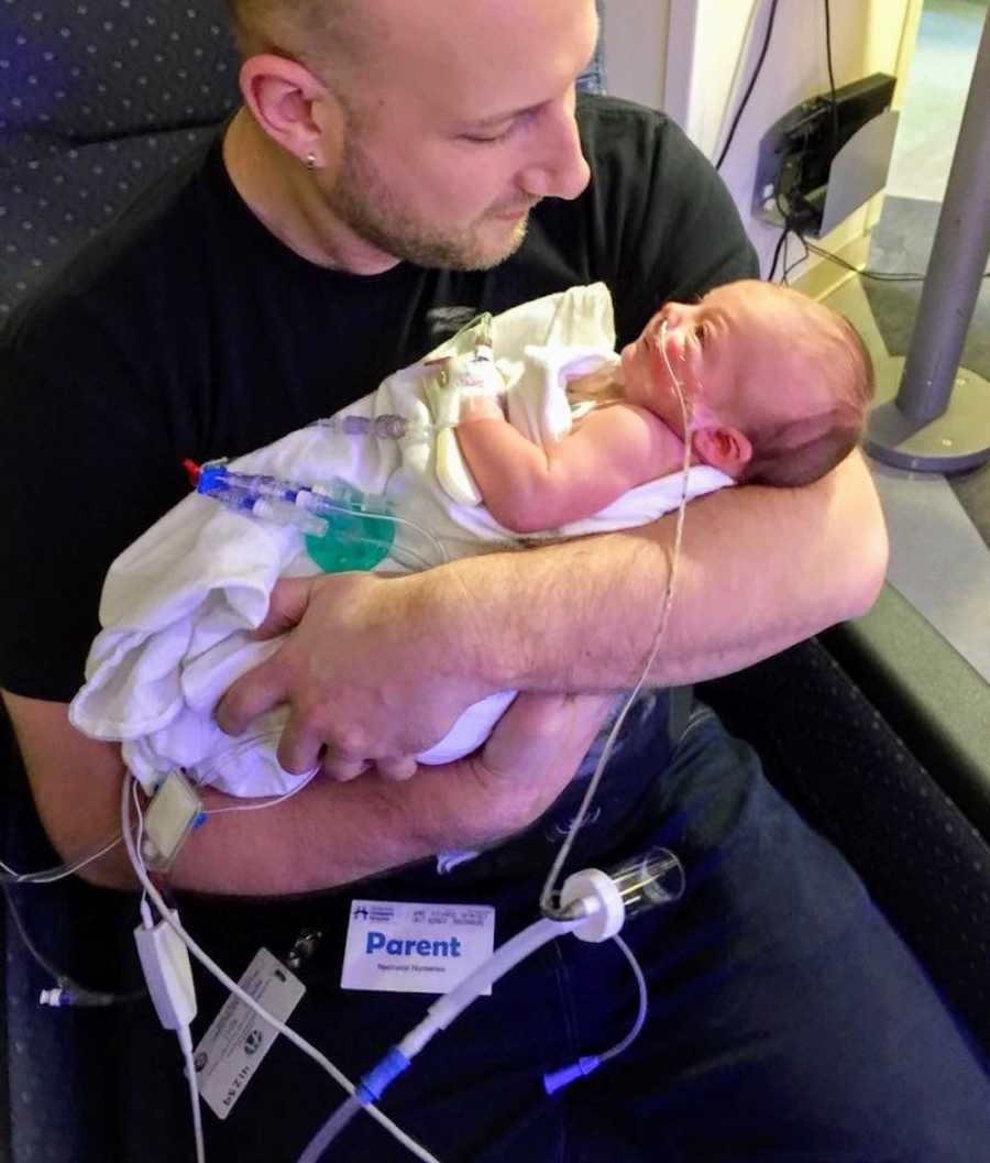Father sits in NICU holding newborn with Hirschsprung Disease